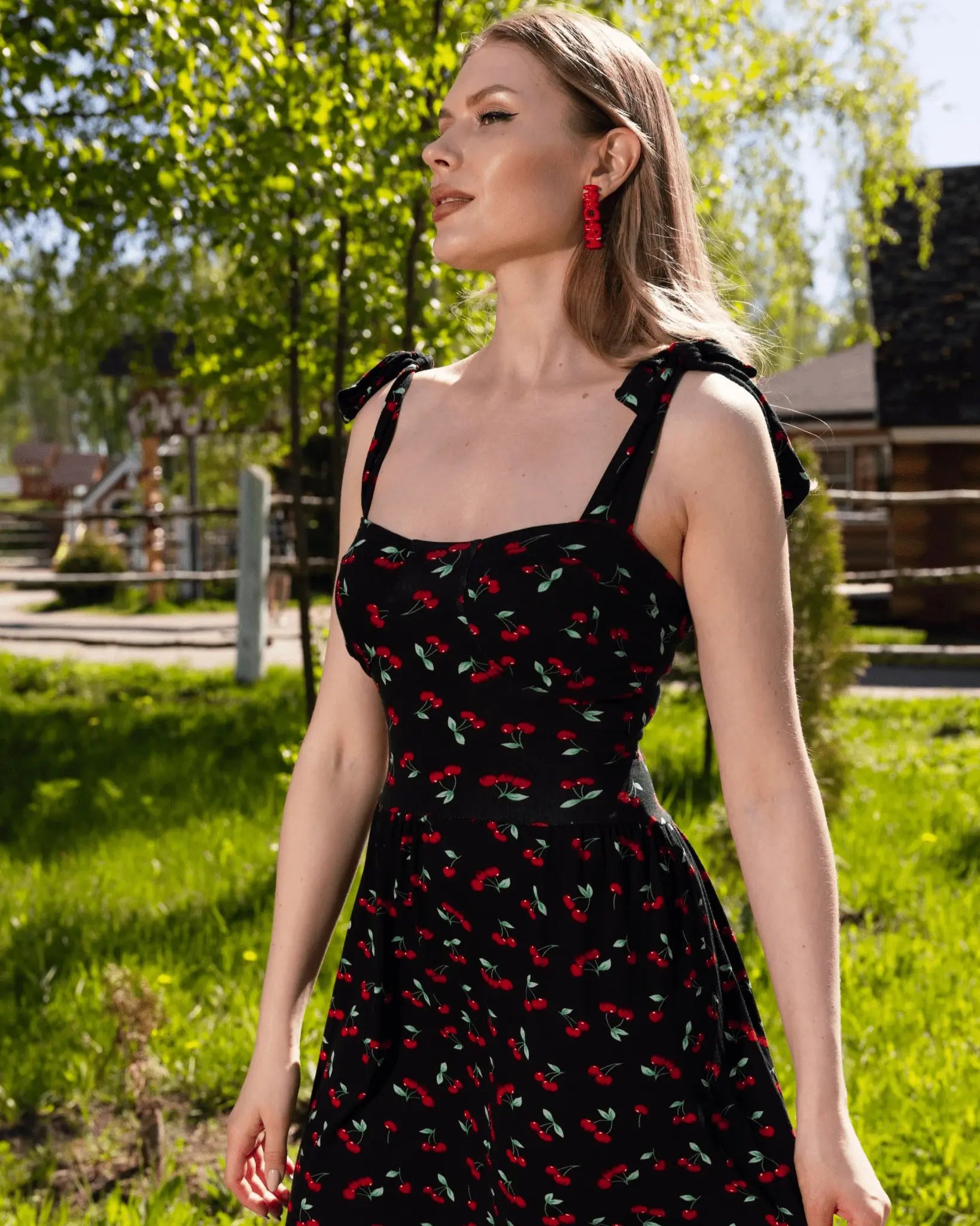 Woman wearing a black dress with red floral patterns outdoors