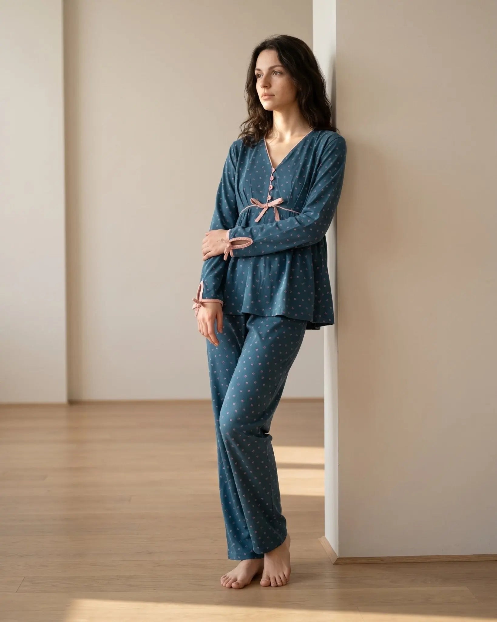 Woman wearing a blue pajama set standing in a minimalistic room.